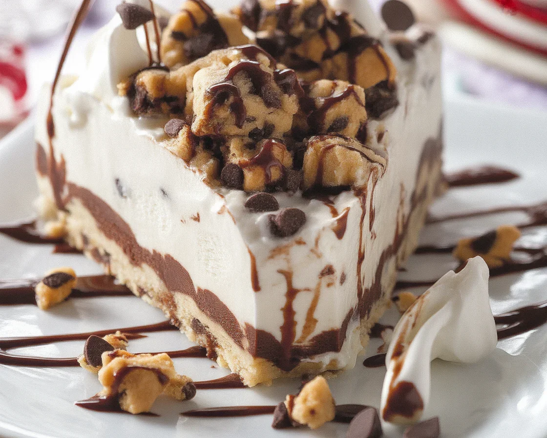 Chocolate chip cookie ice cream cake layered with cookie dough and topped with whipped cream.