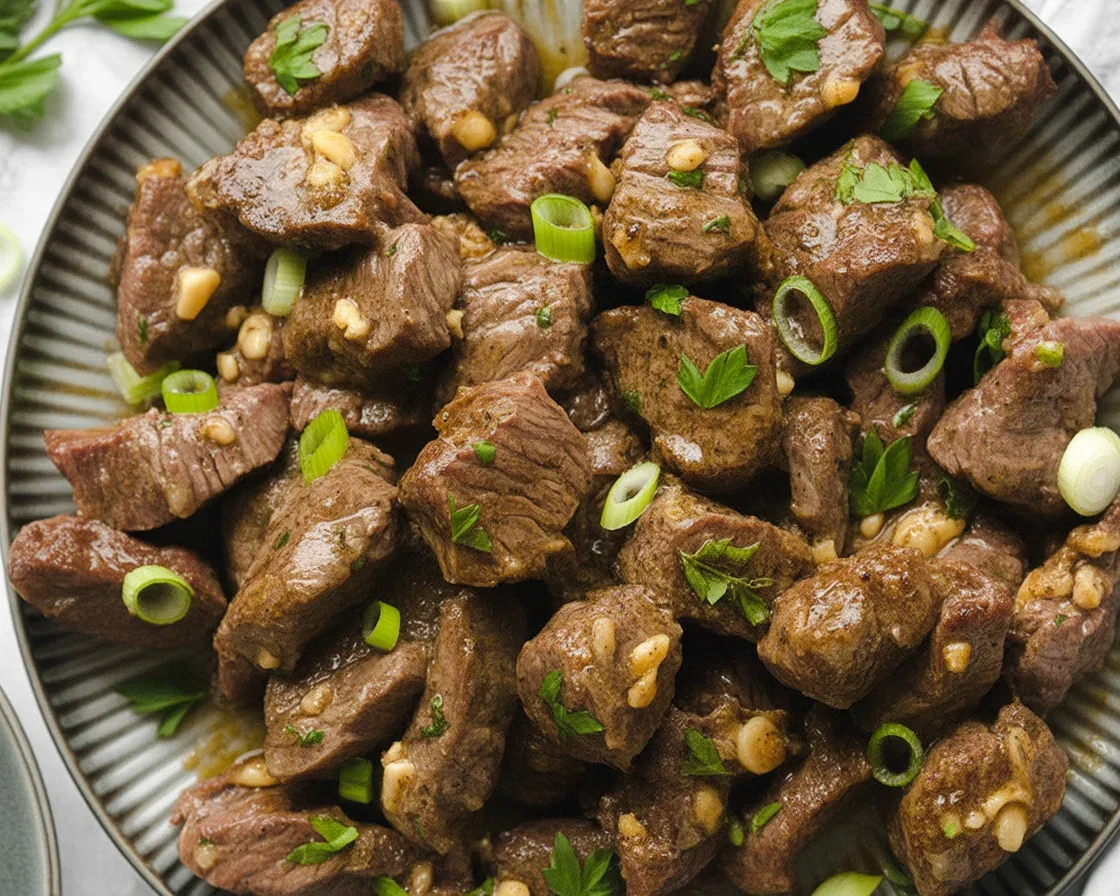 Garlic butter steak bites simmered in aromatic garlic butter sauce, served on a plate.